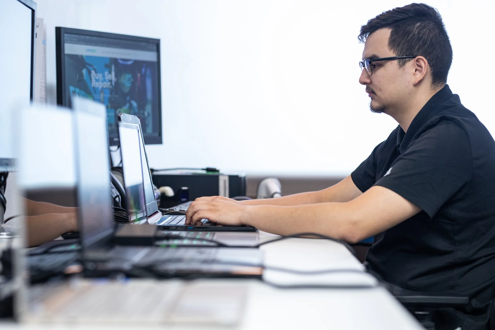 A repair technician at a workstation at Compco USA, working a ticket